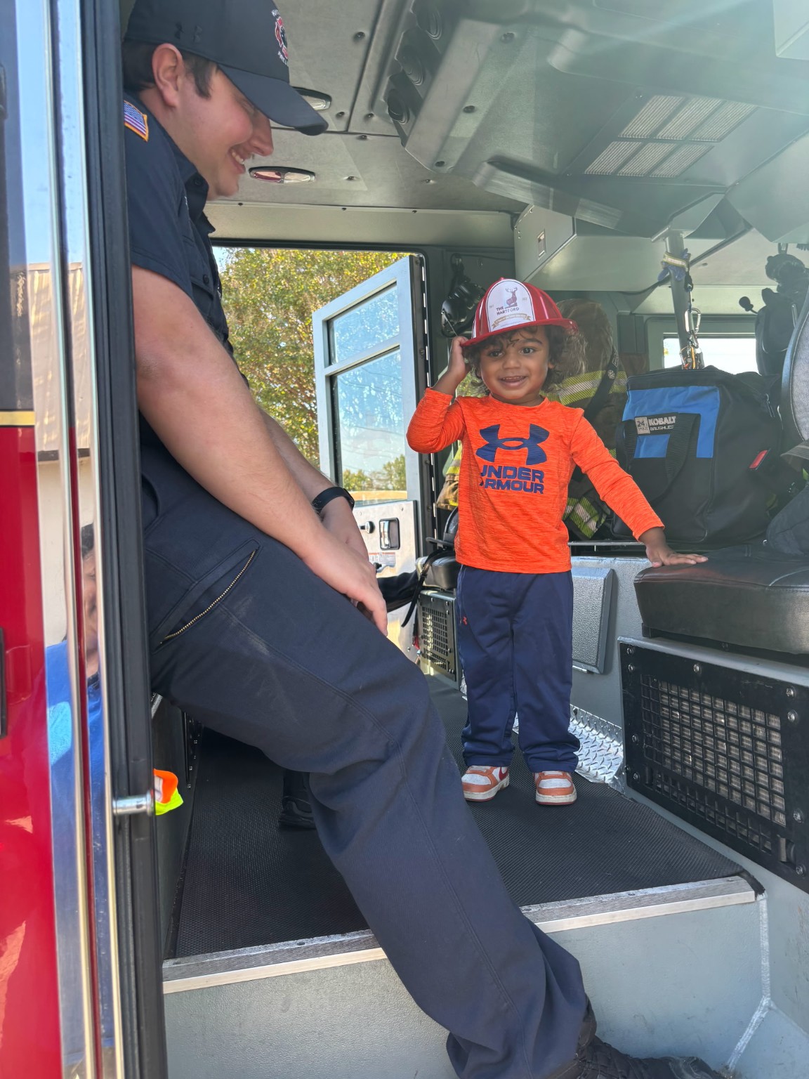 Young World child visiting a fire truck with a firefighter